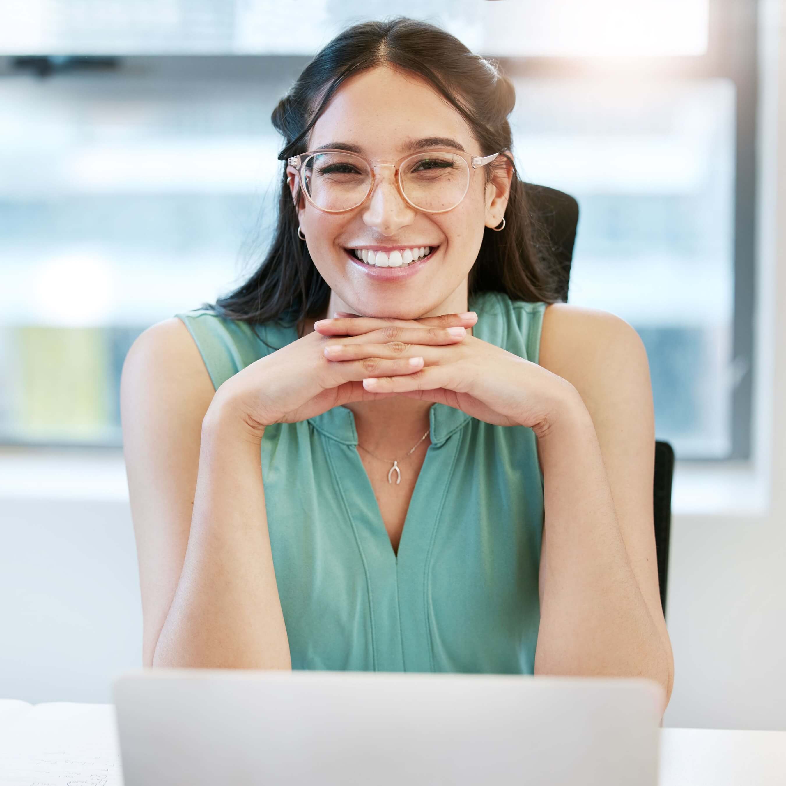Smiling woman with glasses sitting at a desk